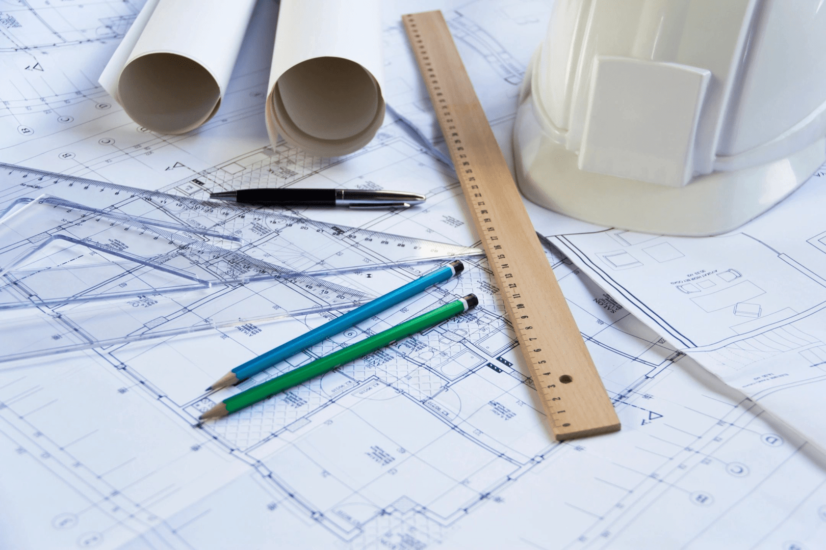 A pair of pencils and ruler on top of construction plans.