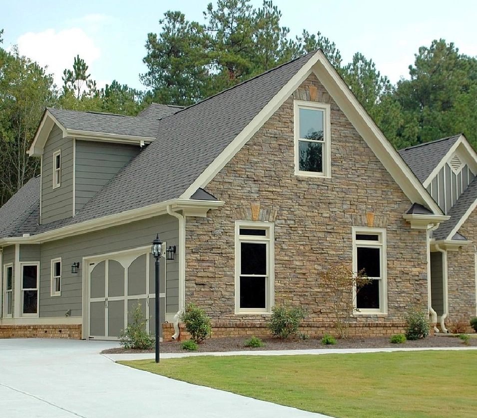 A house with a driveway and trees in the background.