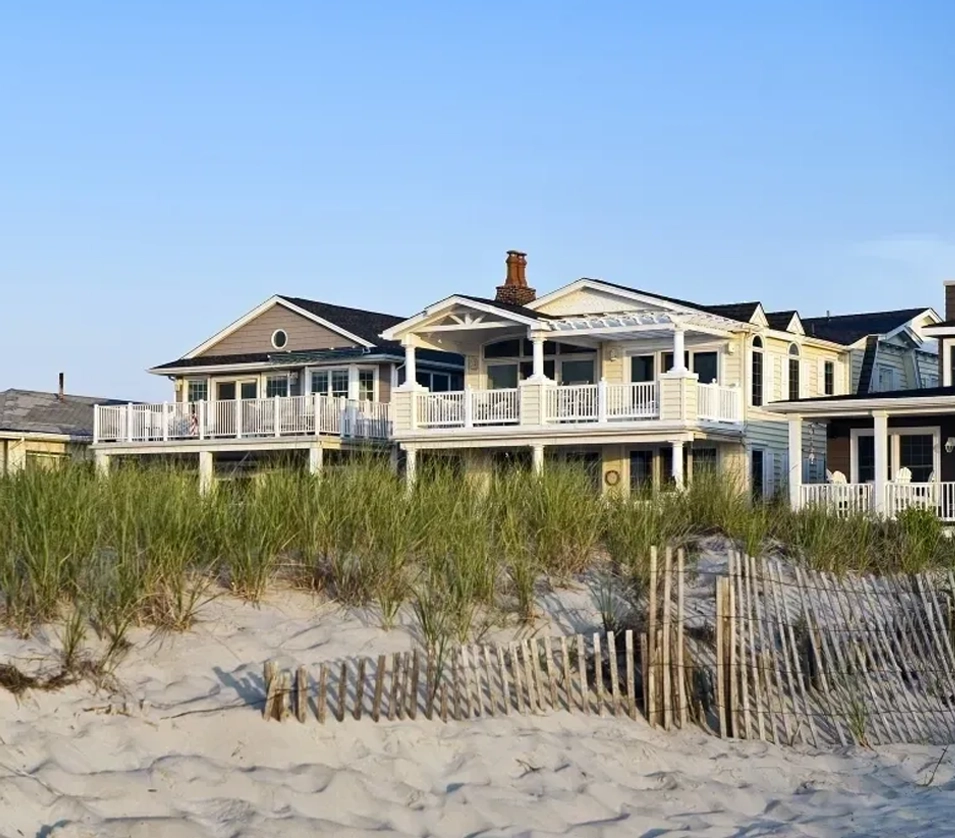 A beach front home with many grass and sand dunes.