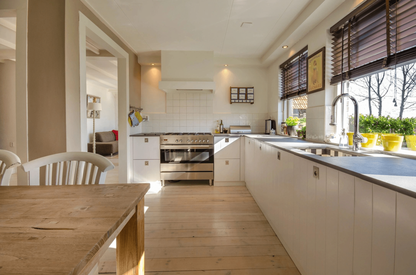 A kitchen with white cabinets and wooden floors.